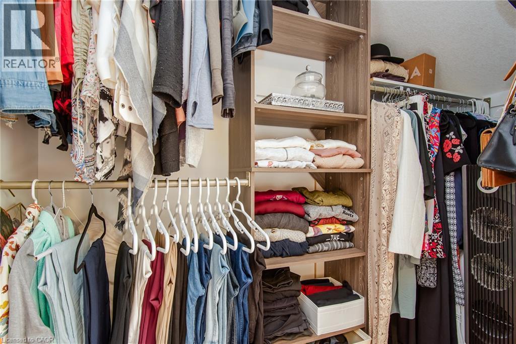 Custom closet organization system featuring wood-finish shelving, multiple hanging rods, and integrated storage compartments - 38 David Bergey Drive, Kitchener, ON - Indoor With Storage