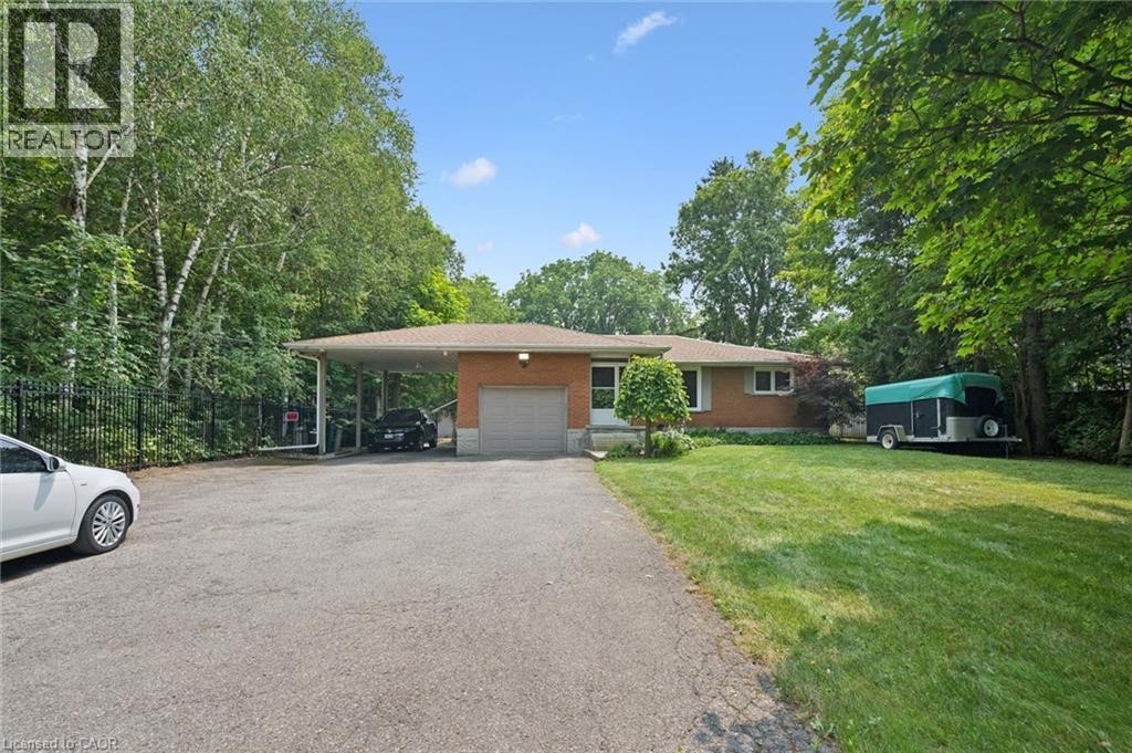 Brick exterior ranch-style residence featuring an attached single-car garage, a covered carport, and a spacious paved driveway - 410 Avenue Road, Cambridge, ON - Outdoor