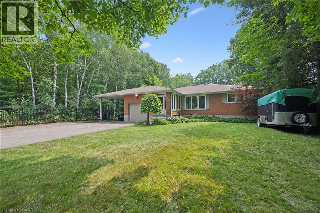 Brick-clad residence featuring a front lawn, paved driveway, and mature perimeter trees, featuring a spacious front lawn with irrigation. - 410 Avenue Road, Cambridge, ON - Outdoor