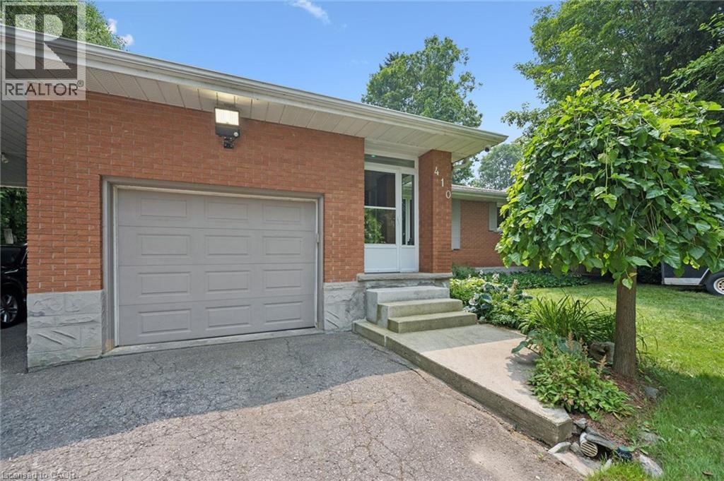 Brick facade residence featuring a single-car garage with a panel door and large LED exterior lighting - 410 Avenue Road, Cambridge, ON - Outdoor With Exterior