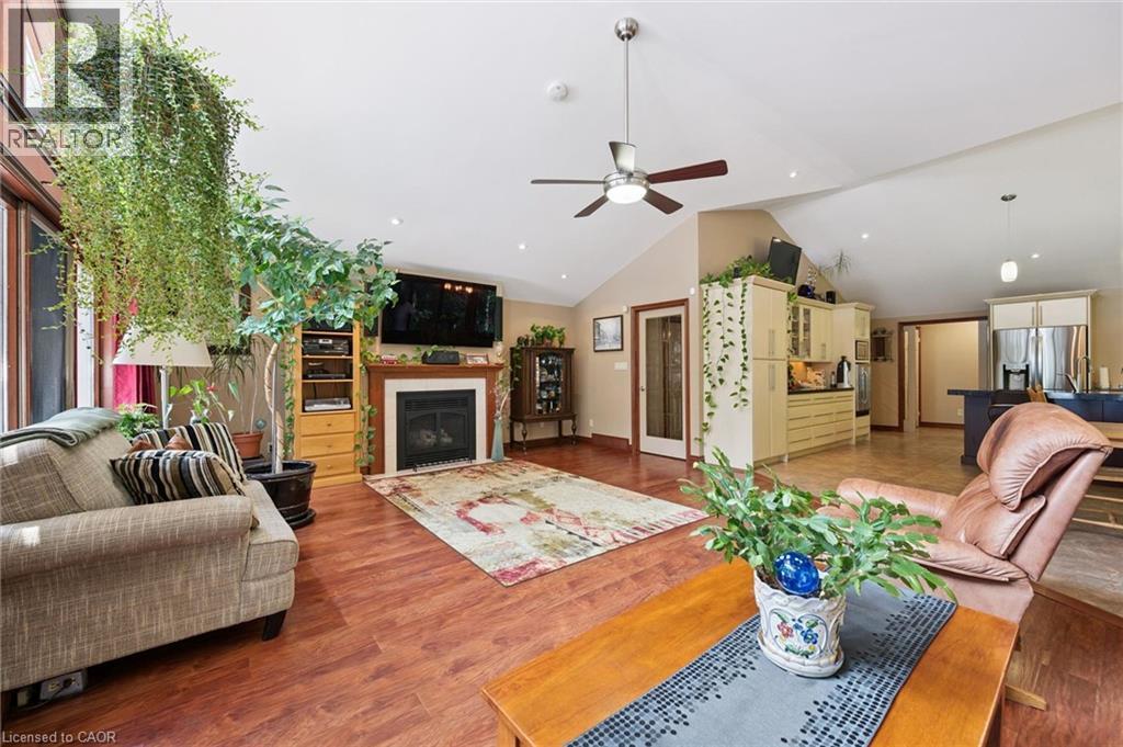 Vaulted ceiling living area featuring wood-finish flooring, a white-mantled fireplace, recessed lighting, with integrated audio/video wiring to a wall mounted TV and rear surround speakers - 410 Avenue Road, Cambridge, ON - Indoor Photo Showing Living Room With Fireplace