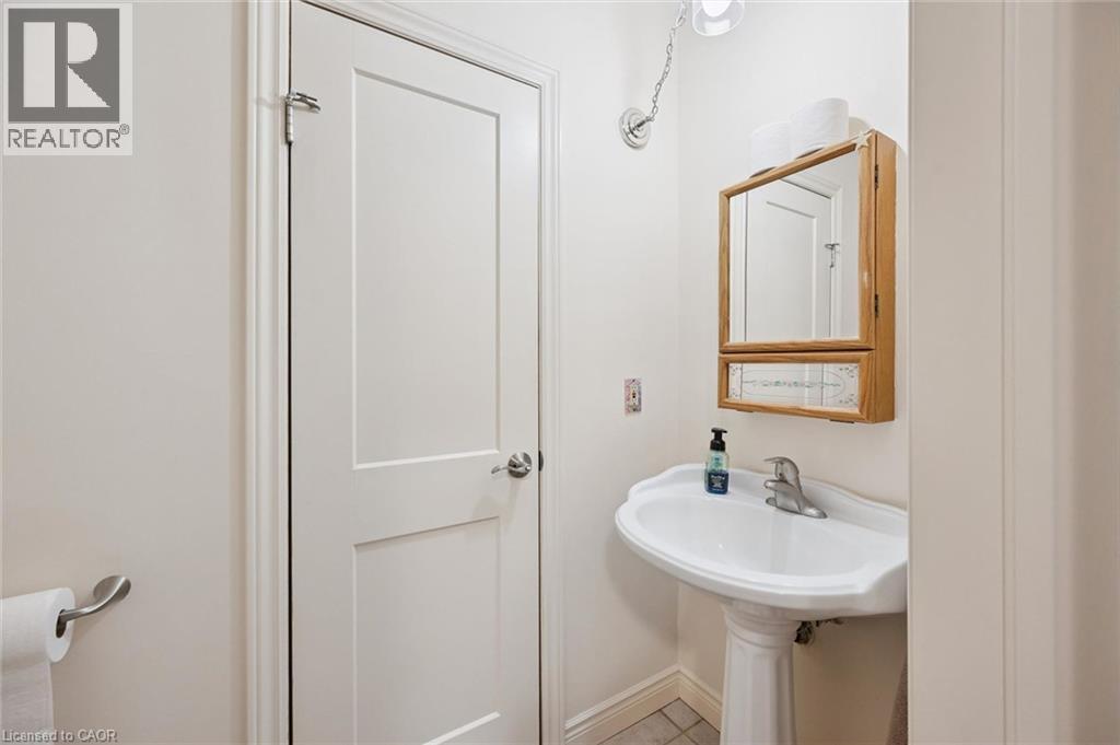 Pedestal sink with chrome faucet, complemented by a wood-framed mirrored medicine cabinet - 410 Avenue Road, Cambridge, ON - Indoor Photo Showing Bathroom