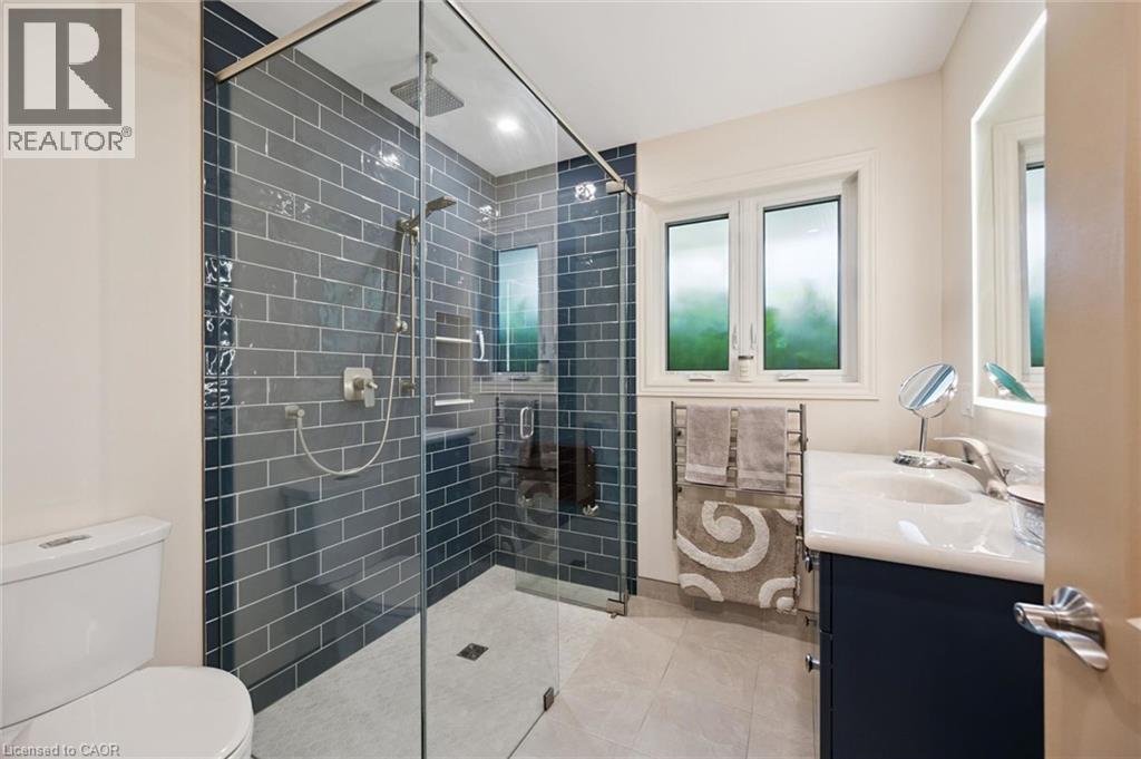 Glass-enclosed shower with subway tile surround, rain shower head, and handheld shower sprayer, but there is also heated towel rack, Moen high-quality stainless-steel shower controls with Moen fold do - 410 Avenue Road, Cambridge, ON - Indoor Photo Showing Bathroom