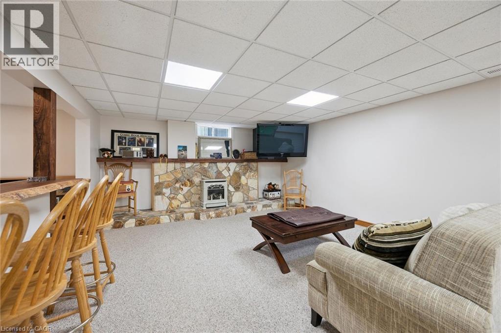 Finished lower level featuring a stone-faced bar with a built-in fireplace, a live-edge wooden bar top, wood-finish support posts, and recessed ceiling lighting - 410 Avenue Road, Cambridge, ON - Indoor