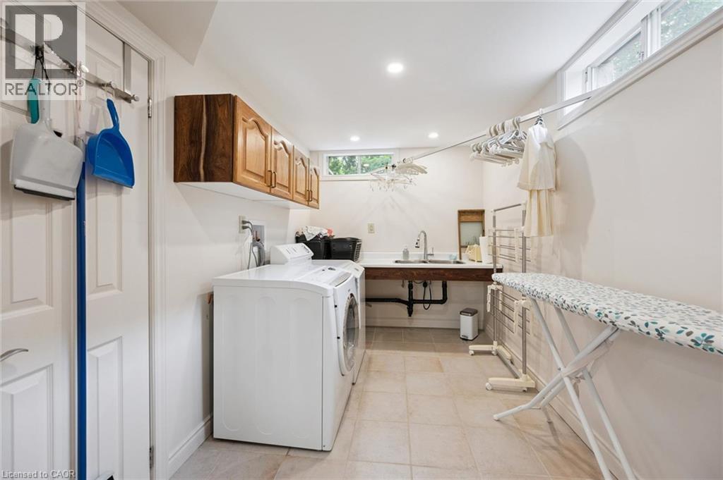 Dedicated laundry room featuring ceramic tile flooring, white walls, recessed lighting, upper cabinetry, dual SST sink and a Bose natural gas dryer - 410 Avenue Road, Cambridge, ON - Indoor Photo Showing Laundry Room