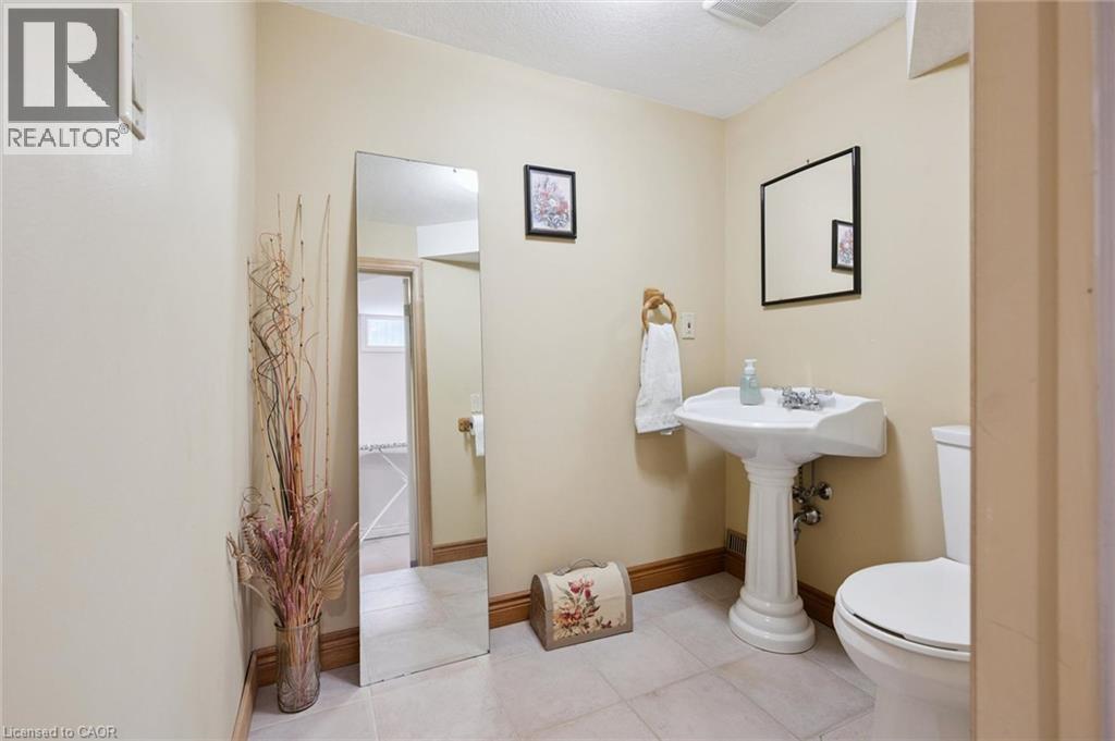 Pedestal sink with chrome fixtures, a wall-mounted mirror, and tile flooring - 410 Avenue Road, Cambridge, ON - Indoor Photo Showing Bathroom