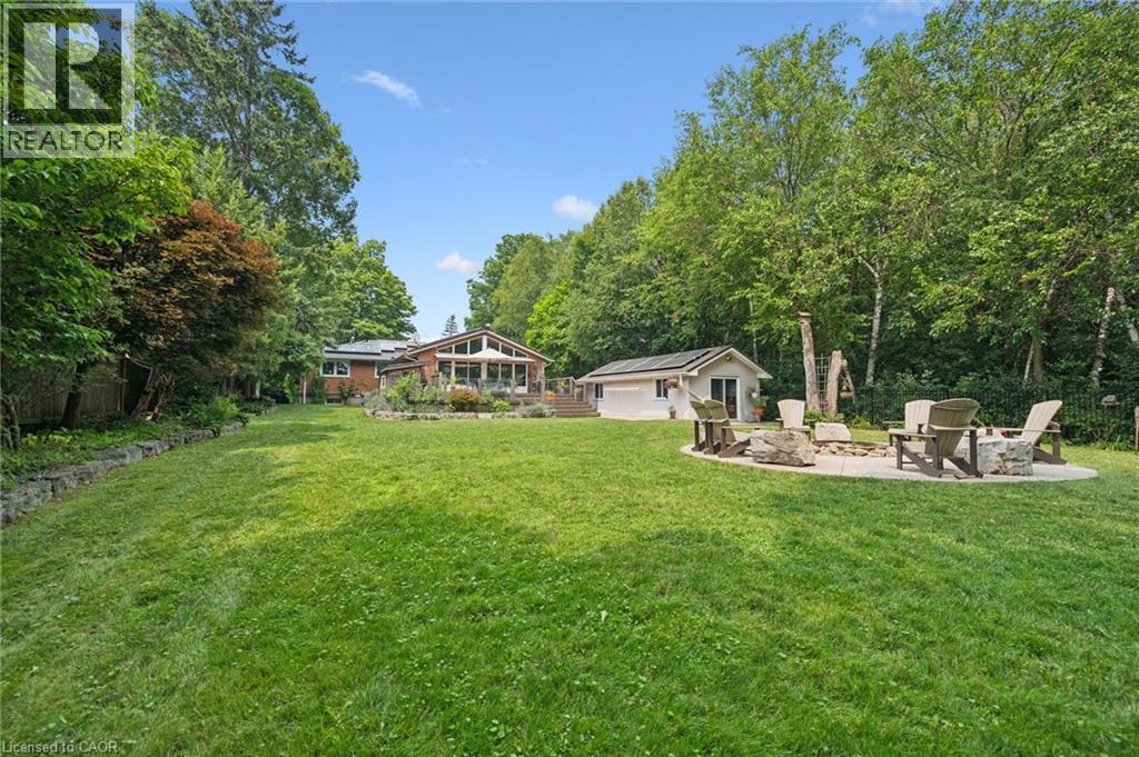 Expansive green lawn with a circular paved fire pit area featuring stone accents - 410 Avenue Road, Cambridge, ON - Outdoor