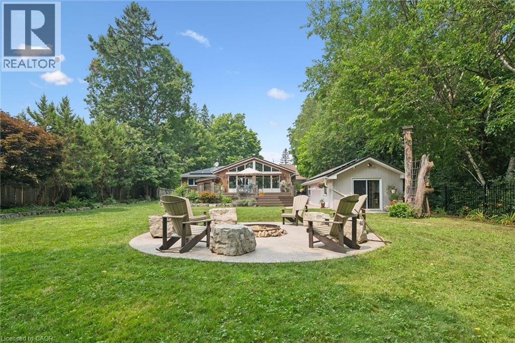Expansive green lawn featuring a circular patio fire pit with stone seating - 410 Avenue Road, Cambridge, ON - Outdoor