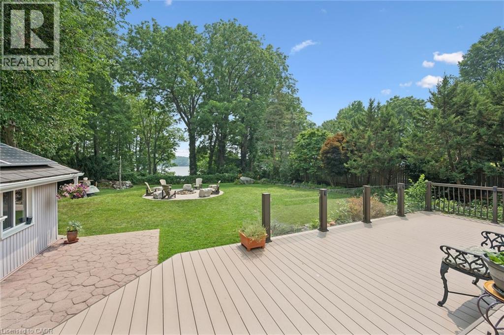 Expansive composite deck overlooking a manicured lawn with fire pit area overlooking a lake - 410 Avenue Road, Cambridge, ON - Outdoor With Backyard