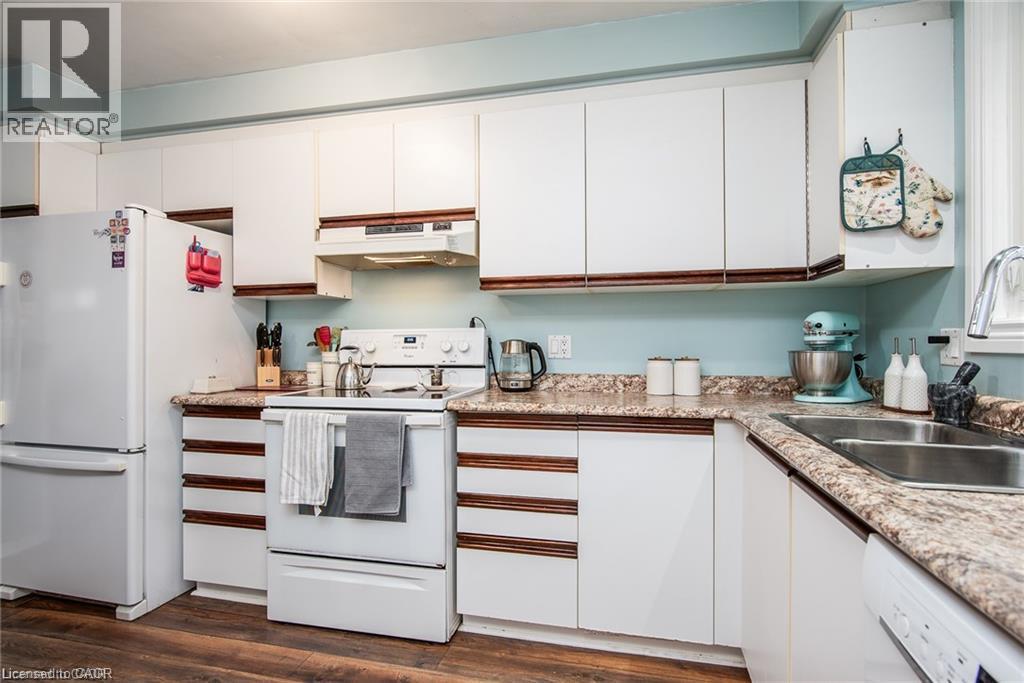 Kitchen featuring white cabinetry with wood-finish trim, laminate countertops, and wood-finish flooring - 67 Pinemeadow Crescent, Waterloo, ON - Indoor Photo Showing Kitchen With Double Sink
