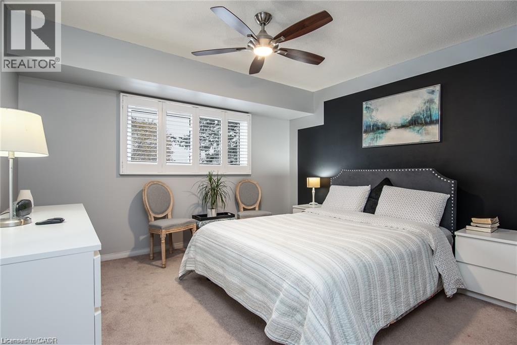 Bedroom featuring a ceiling fan with integrated lighting, a dark accent wall, and a window with plantation shutters - 67 Pinemeadow Crescent, Waterloo, ON - Indoor Photo Showing Bedroom