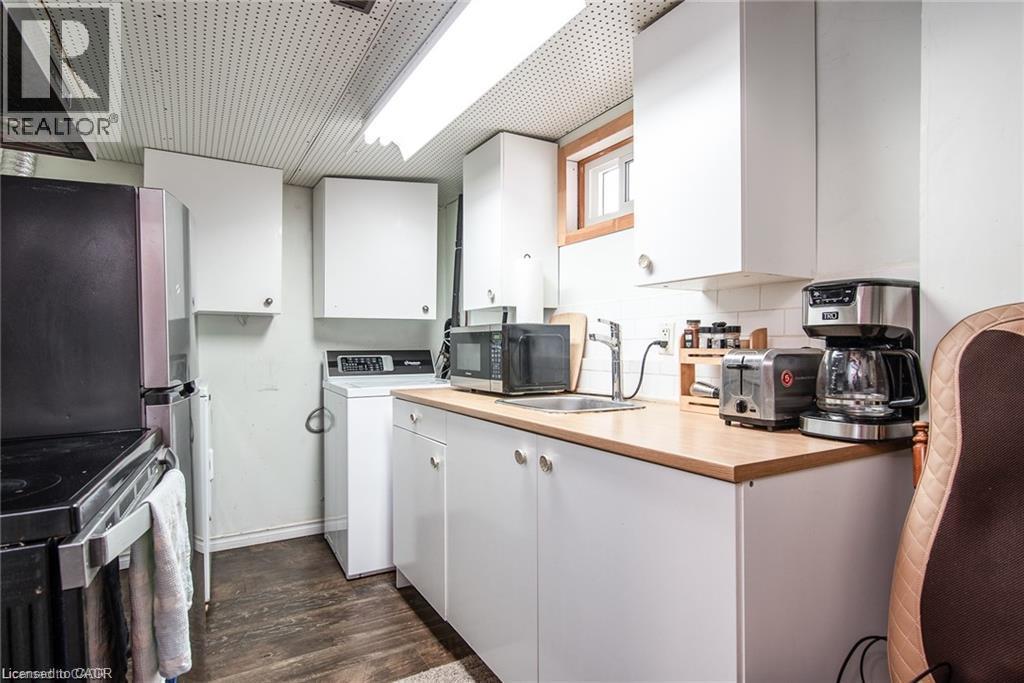 Compact kitchenette featuring white cabinetry, light wood-finish countertops, and a single basin sink - 67 Pinemeadow Crescent, Waterloo, ON - Indoor Photo Showing Kitchen