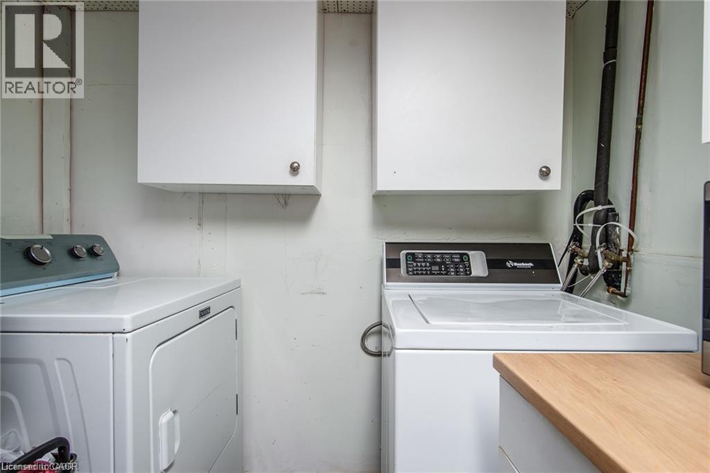 Dedicated laundry area featuring white wall cabinetry, a wood-finish countertop, and visible plumbing - 67 Pinemeadow Crescent, Waterloo, ON - Indoor Photo Showing Laundry Room