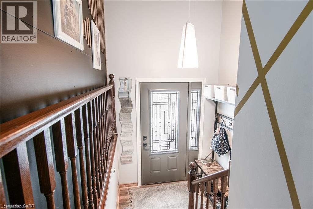 Foyer with a paneled entry door featuring decorative glass and coordinating sidelights, a two-story ceiling, a contemporary pendant light fixture, and a built-in coat rack with shelving - 67 Pinemeadow Crescent, Waterloo, ON - Indoor Photo Showing Other Room