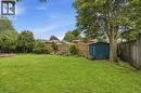 Expansive backyard featuring a manicured lawn, established trees, a blue storage shed, and a stone-lined fire pit area - 834 Mohawk Road E, Hamilton, ON  - Outdoor 