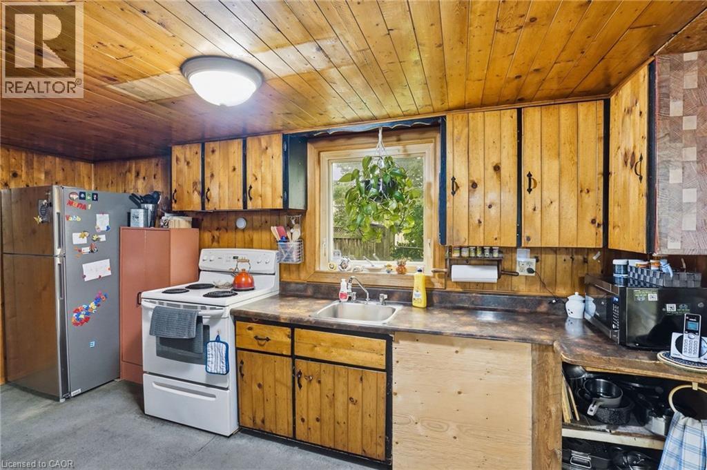 Kitchen featuring wood paneling, wood-finish cabinetry, built-in sink, window, and overhead lighting - 834 Mohawk Road E, Hamilton, ON - Indoor Photo Showing Kitchen