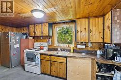 Kitchen featuring wood paneling, wood-finish cabinetry, built-in sink, window, and overhead lighting -