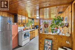 Kitchen featuring extensive wood paneling, a stainless steel refrigerator, white electric range, and a double basin sink -
