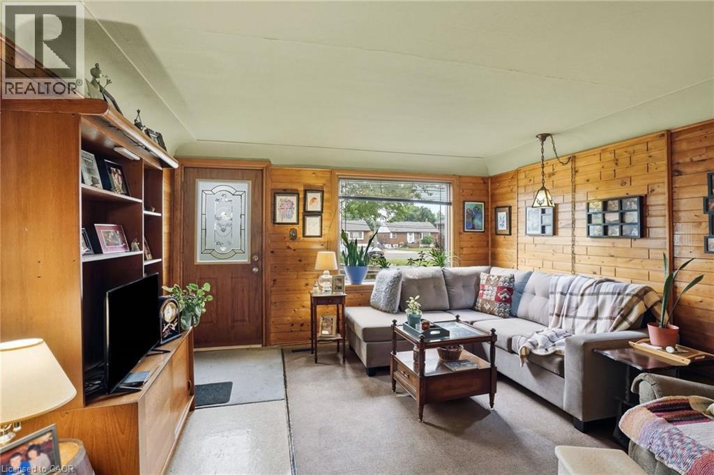 Living area featuring wood paneling, a front entry door with decorative glass, and a large bay window - 834 Mohawk Road E, Hamilton, ON - Indoor Photo Showing Living Room