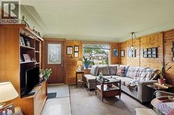 Living area featuring wood paneling, a front entry door with decorative glass, and a large bay window -