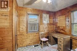 Paneled room featuring wood-finish walls, a window with blinds, and ceiling-mounted lighting -