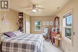 Carpeted room featuring two windows, a ceiling fan with integrated lighting, built-in shelving, and integrated cabinetry -