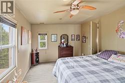 Carpeted room featuring multiple windows with tree-lined exterior, light-toned walls, and a ceiling fan with integrated lighting -