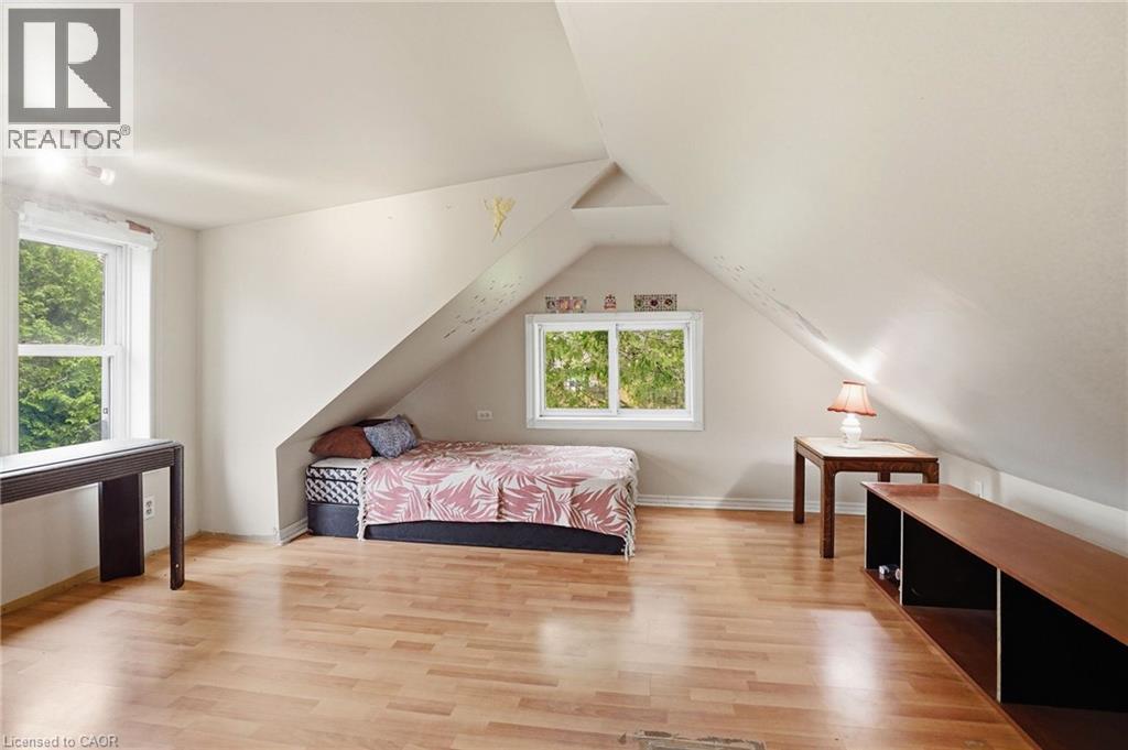 Attic room featuring light wood-finish flooring, white walls, and a sloped ceiling - 834 Mohawk Road E, Hamilton, ON - Indoor Photo Showing Bedroom