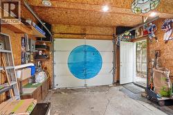 Garage interior featuring oriented strand board walls and ceiling, exposed garage door track, and an exterior access door -