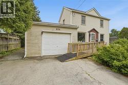 Two-story residence with light-toned siding, attached single-car garage, and a wooden access ramp leading to the main entry -