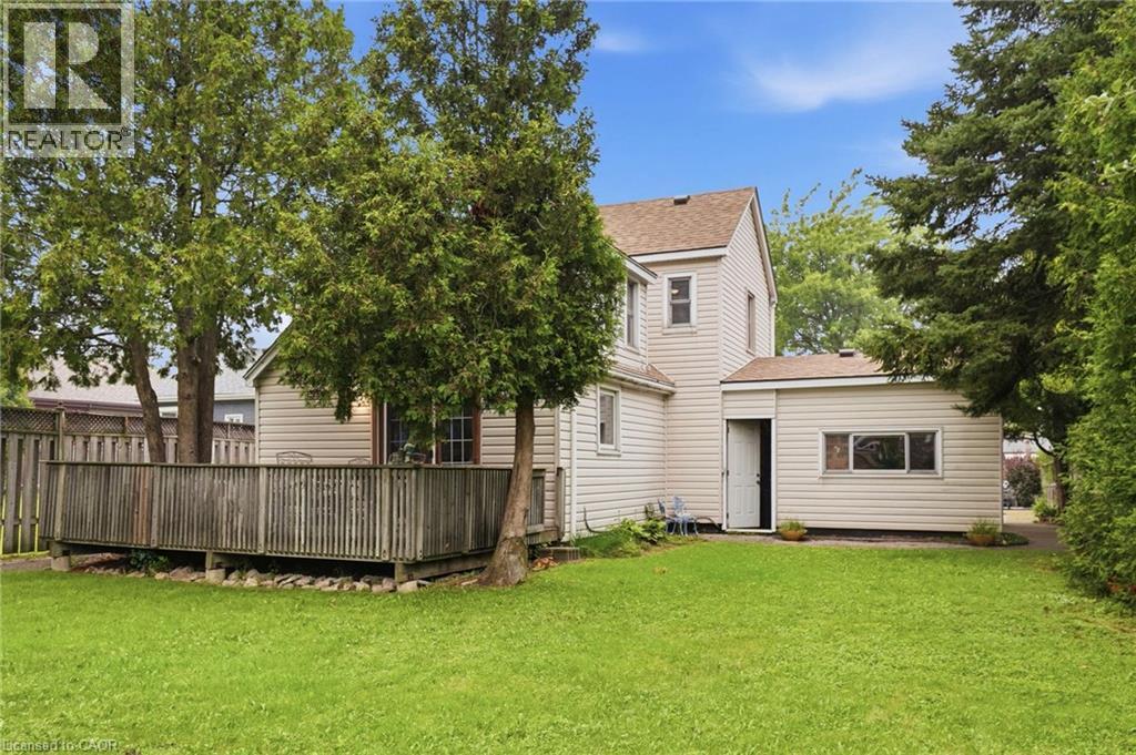 Expansive grassy yard featuring a wooden deck with railing, mature trees, and a privacy fence - 834 Mohawk Road E, Hamilton, ON - Outdoor