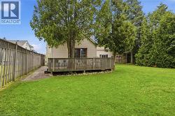 Spacious backyard featuring a wooden deck, mature trees, and a wooden privacy fence -