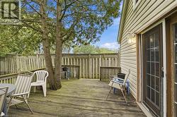 Spacious wood-finish deck bordered by a privacy fence, featuring mature trees and a sliding glass door for outdoor access -