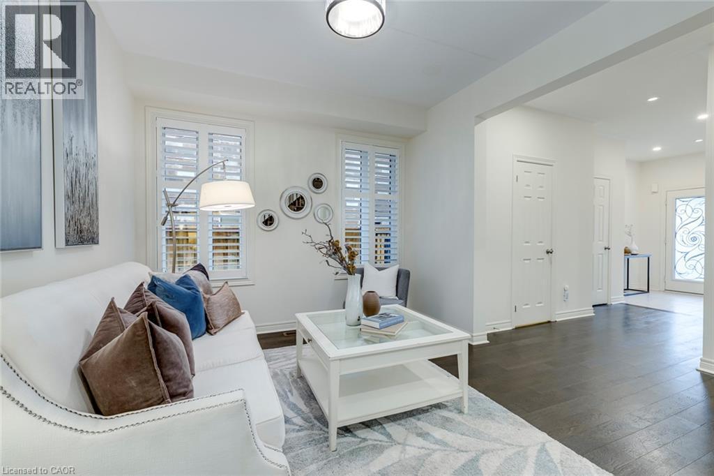 Living area featuring white walls, dark wood-finish flooring, and a recessed ceiling light - 598 Bessborough Drive, Milton, ON - Indoor