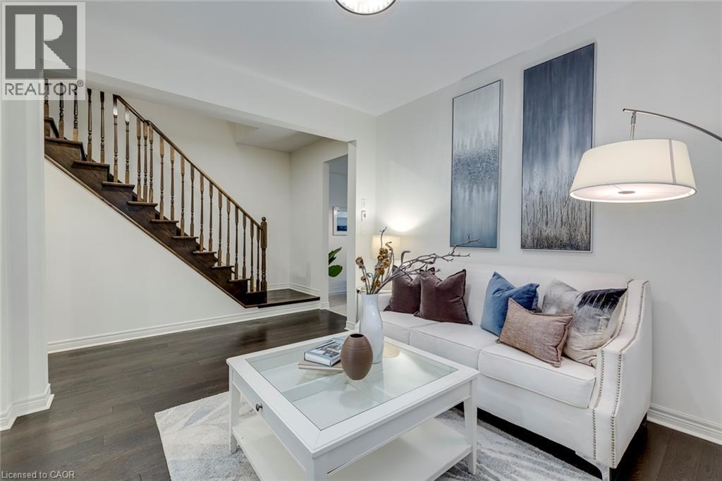 Dark wood-finish flooring complements a staircase with dark wood treads and a spindle banister - 598 Bessborough Drive, Milton, ON - Indoor Photo Showing Living Room