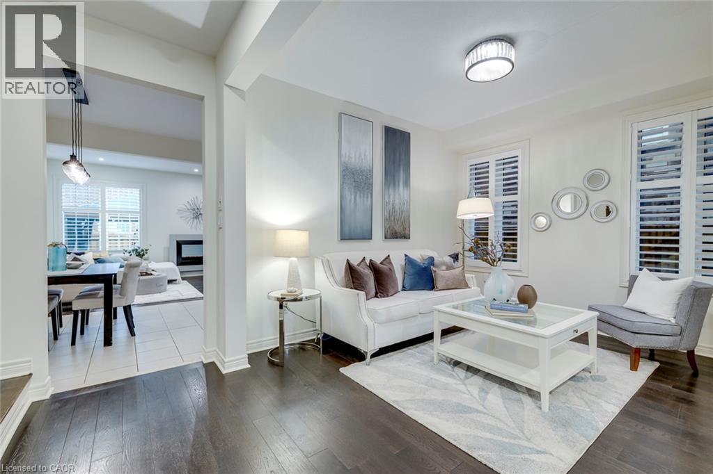 Living room featuring dark wood-finish flooring and white plantation shutters - 598 Bessborough Drive, Milton, ON - Indoor Photo Showing Living Room