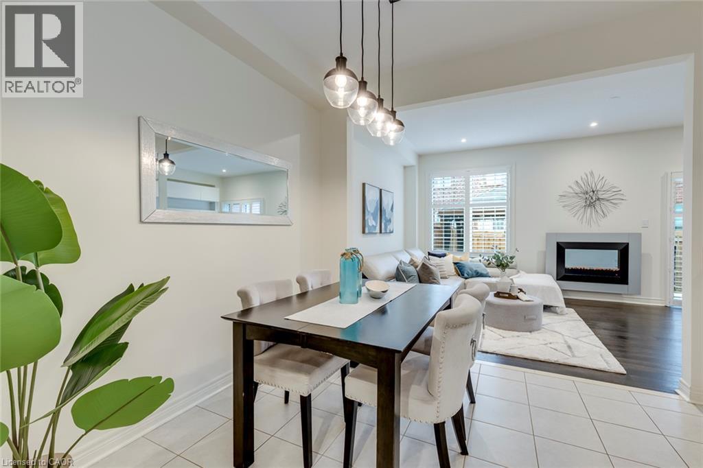 Dining area featuring white tile flooring and a dark wood-finish dining table - 598 Bessborough Drive, Milton, ON - Indoor Photo Showing Dining Room With Fireplace