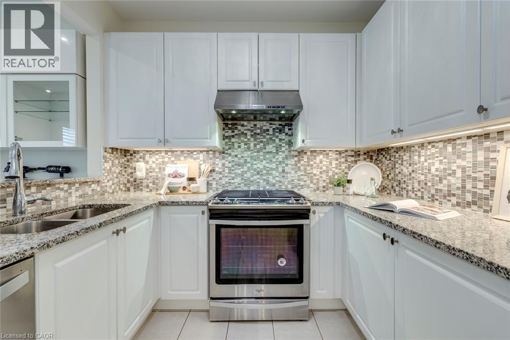 Kitchen featuring white cabinetry, granite countertops, a mosaic tile backsplash, stainless steel appliances, and tile flooring - 598 Bessborough Drive, Milton, ON - Indoor Photo Showing Kitchen With Double Sink With Upgraded Kitchen