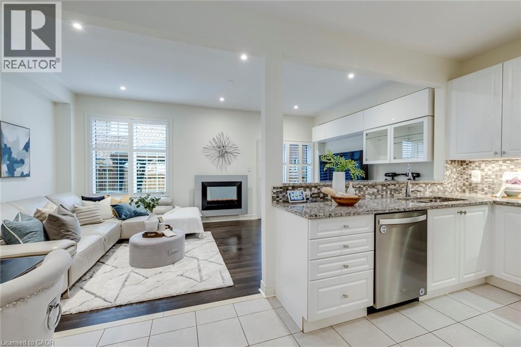 Kitchen featuring granite countertops, mosaic tile backsplash, white cabinetry, and stainless steel dishwasher - 598 Bessborough Drive, Milton, ON - Indoor Photo Showing Kitchen With Fireplace With Upgraded Kitchen