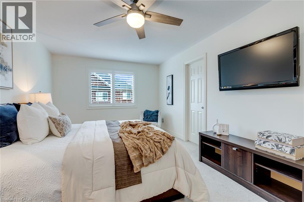 Bedroom featuring a window with white shutters, a ceiling fan with integrated lighting, and light-toned wall-to-wall carpeting - 598 Bessborough Drive, Milton, ON - Indoor Photo Showing Bedroom