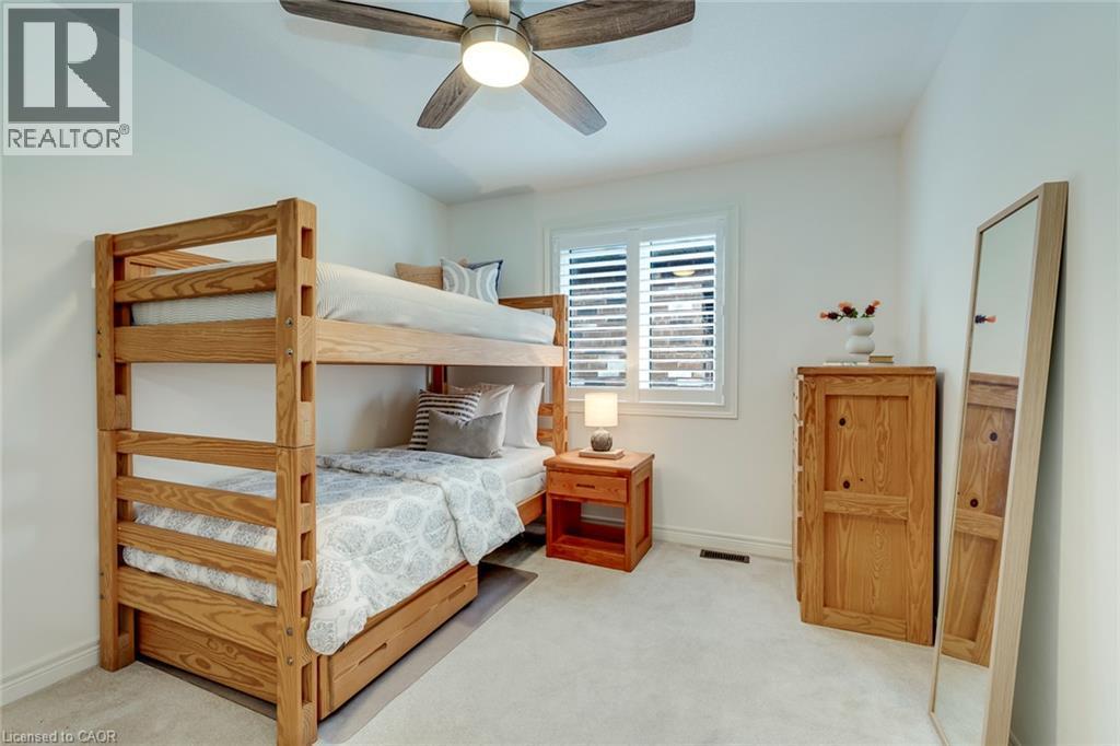 Spacious room featuring light-colored carpeting, a ceiling fan with integrated lighting, and a window with plantation shutters - 598 Bessborough Drive, Milton, ON - Indoor Photo Showing Bedroom