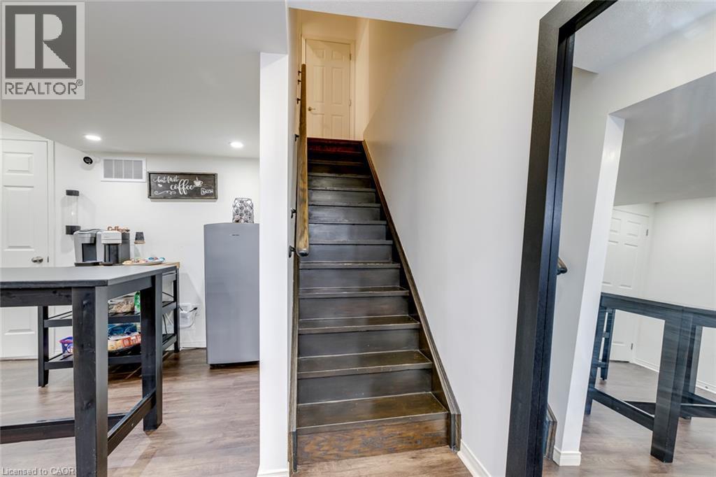 Staircase with dark wood-finish treads and risers, featuring a wood handrail and white wall trim - 598 Bessborough Drive, Milton, ON - Indoor Photo Showing Other Room