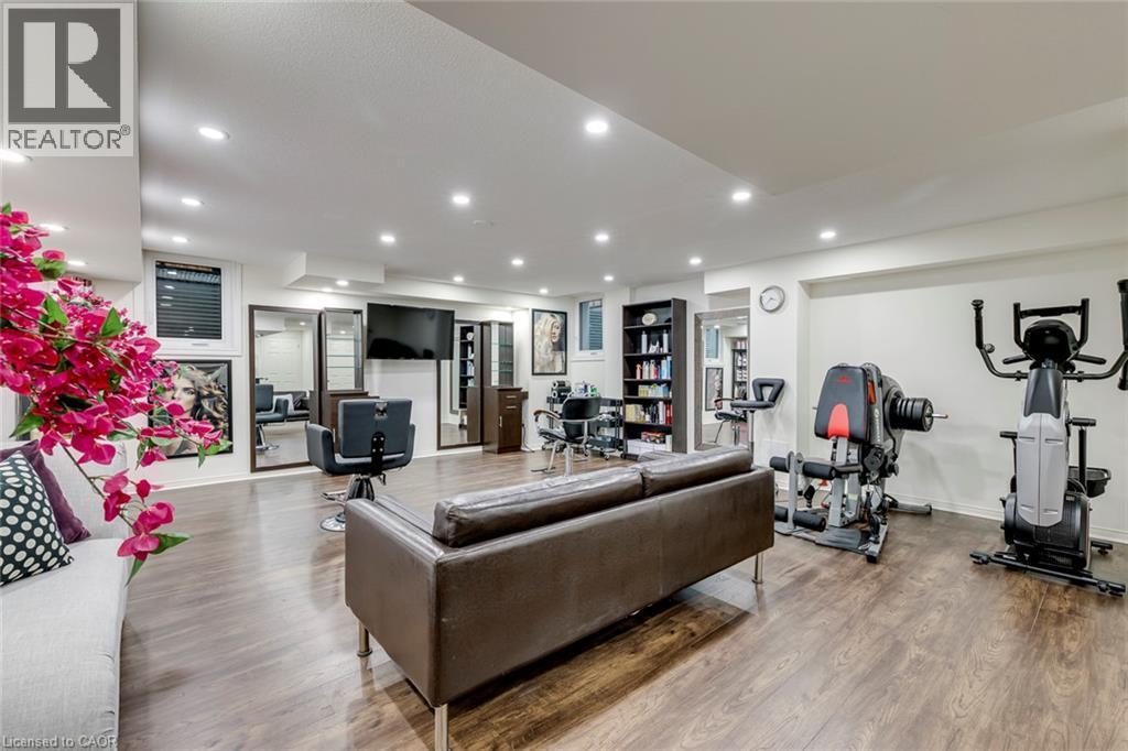 Spacious lower level featuring wood-finish flooring, recessed lighting, multiple windows, and a dedicated fitness area - 598 Bessborough Drive, Milton, ON - Indoor Photo Showing Gym Room