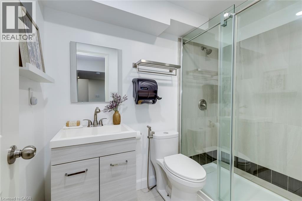 Bathroom featuring a glass-enclosed shower, single vanity with light wood-finish cabinetry, contemporary sink, and brushed nickel fixtures - 598 Bessborough Drive, Milton, ON - Indoor Photo Showing Bathroom