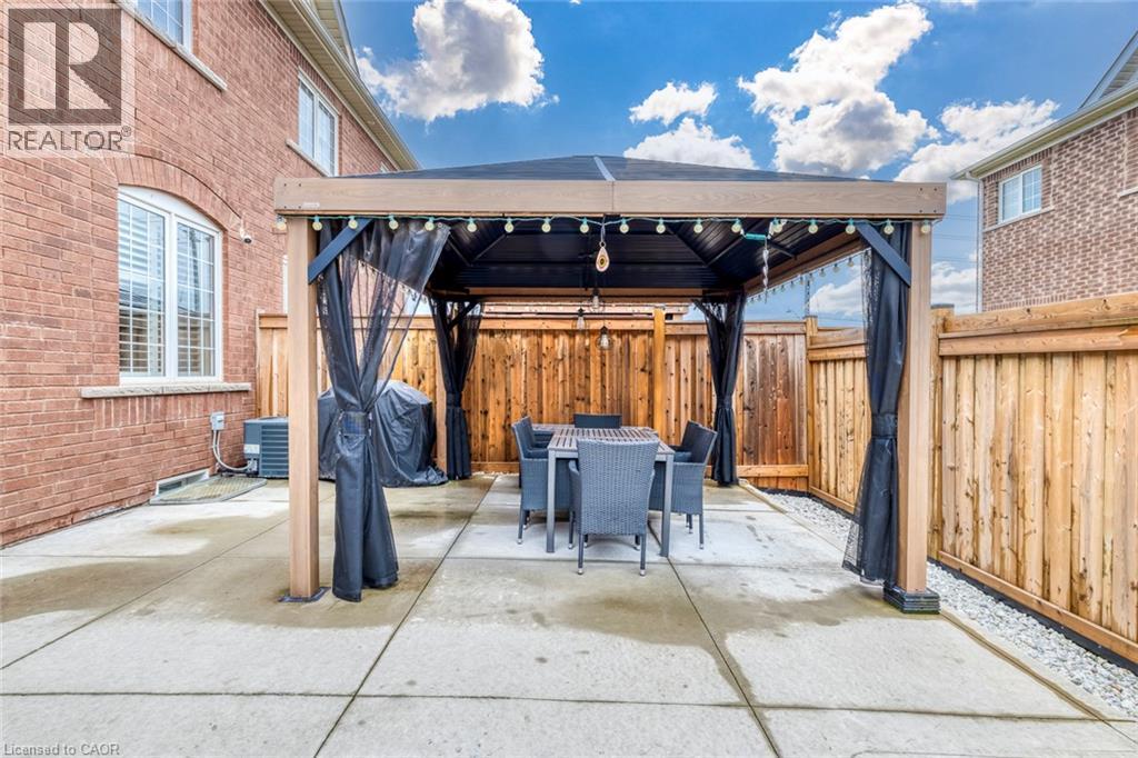 Concrete patio featuring a built-in gazebo with a dark fabric canopy and screening - 598 Bessborough Drive, Milton, ON - Outdoor With Exterior