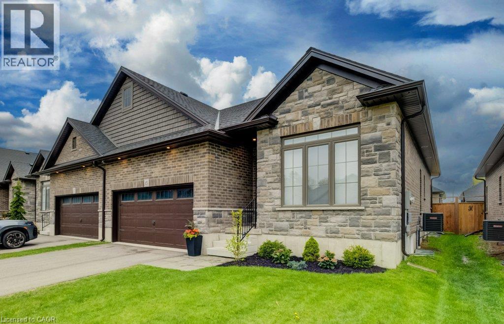 Contemporary exterior featuring a combination of brick and stone cladding, a two-car garage with dark wood-finish doors, and a well-maintained front lawn - 15 Matheson Crescent, Innerkip, ON - Outdoor