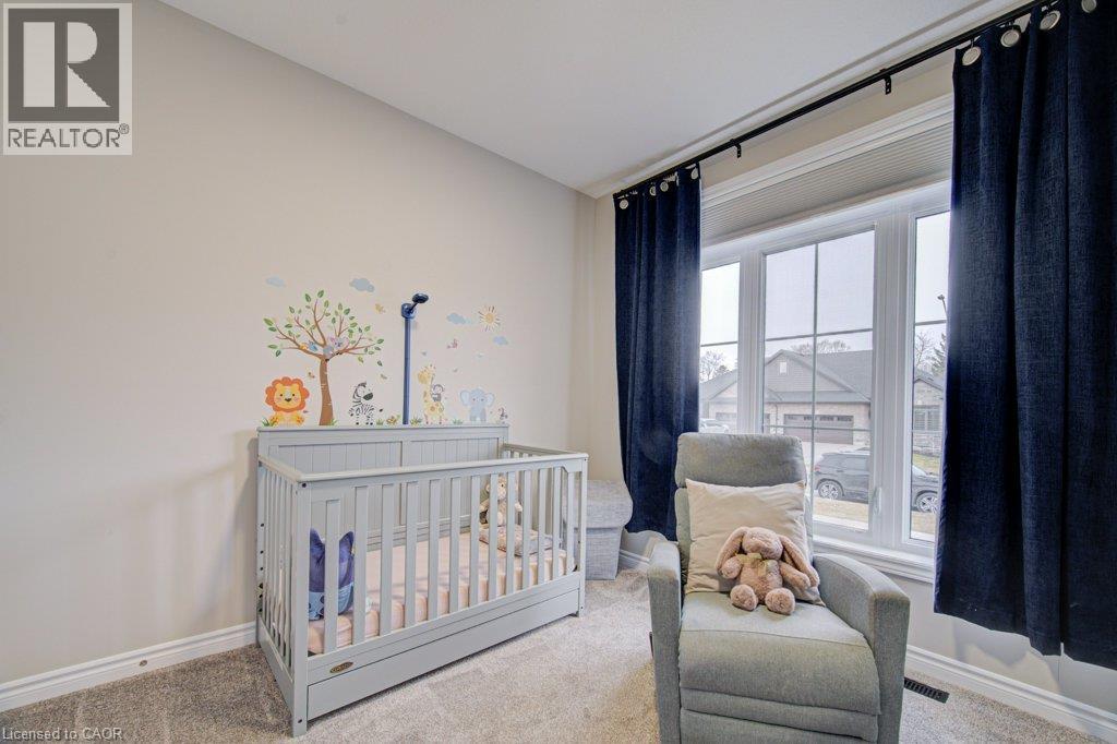 Bright room featuring neutral walls, carpeting, and a large window with deep blue drapes - 15 Matheson Crescent, Innerkip, ON - Indoor Photo Showing Bedroom