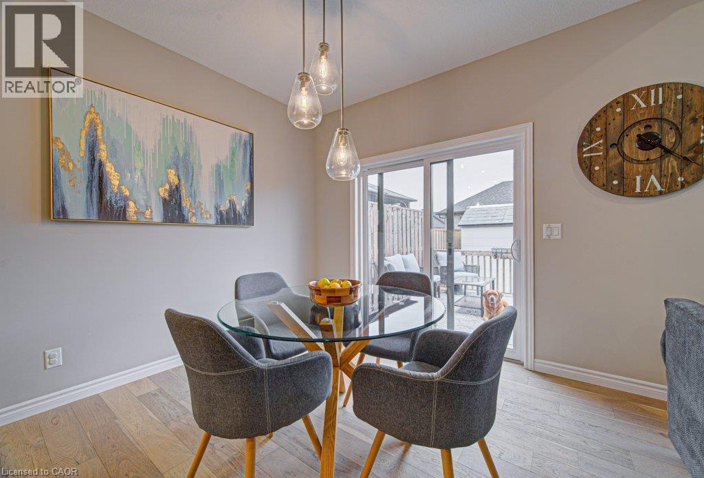 Dining area featuring light wood-finish flooring, a contemporary pendant light fixture, and a sliding glass door providing outdoor access to a deck - 15 Matheson Crescent, Innerkip, ON - Indoor Photo Showing Dining Room