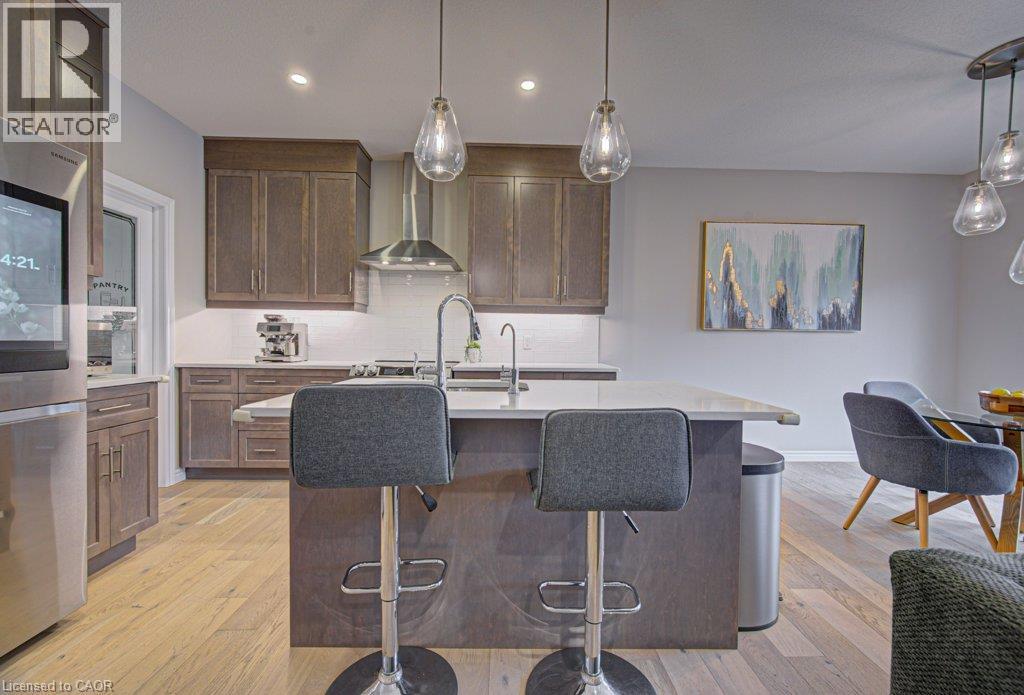 Kitchen featuring wood-finish cabinetry, stainless steel appliances, a center island with countertop seating, and light wood-finish flooring - 15 Matheson Crescent, Innerkip, ON - Indoor