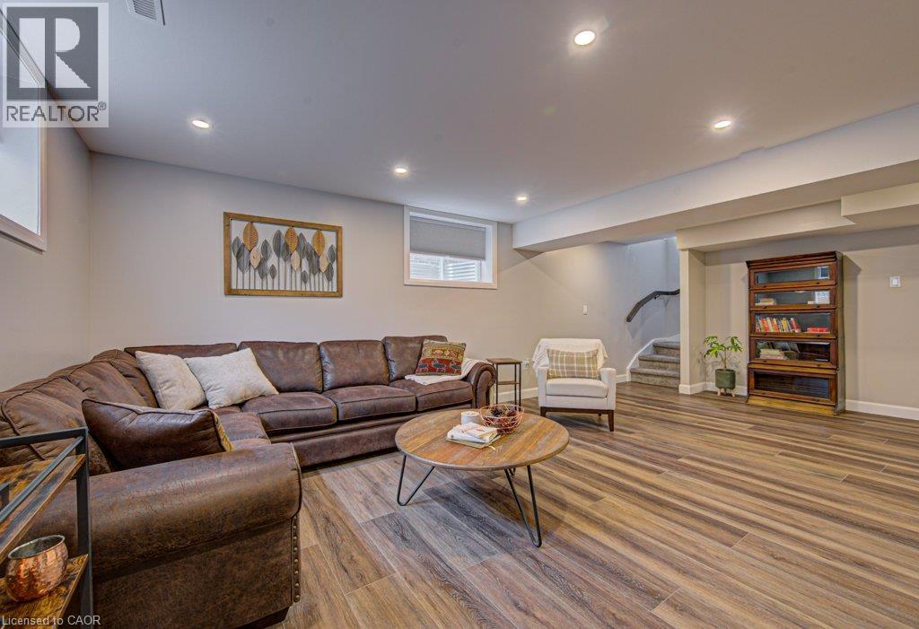 Finished lower level offering recessed lighting, wood-finish flooring, windows, and carpeted stairs with a dark wood handrail - 15 Matheson Crescent, Innerkip, ON - Indoor